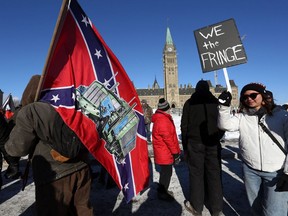 A supporter carries a U.S. Confederate battle flag during the Freedom Convoy protesting  COVID-19 vaccine mandates and restrictions in front of Parliament on January 29, 2022 in Ottawa, Canada.