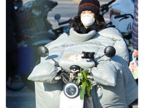 A woman stays warm while riding a motor scooter in Beijing during the Beijing 2022 Winter Olympics on Sunday, January 30, 2022. 

Gavin Young/Postmedia