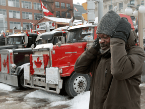 A man covers his ears while passing honking trucks in Ottawa on Thursday. Lots is known about the health risks of noise, including cardiovascular disease, cognitive impairment, sleep disturbance and mental health impacts.