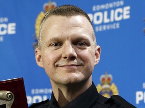 Kiwanis 2017 Top Cop Award winner Const. Michael Zacharuk shows his plaque after a ceremony held at Edmonton Police Service Headquarters in Edmonton in March 2018. On Thursday he was arrested and charged with assault.