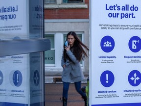 Masked pedestrians walk by a COVID-19 safety sign outside the Best Buy on 17 Ave. S.W. on Thursday, February 3, 2022. Azin Ghaffari/Postmedia