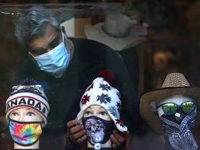 Amin Badani adjusts the masks in a window display at the Kanata Trading Post store on Stephen Avenue in downtown Calgary on Nov. 5, 2021.