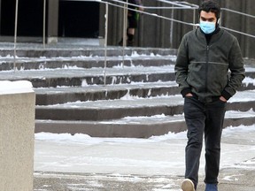 A person is seen wearing a mask walking downtown on Wednesday, February 16, 2022.