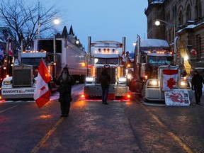 A protester stands near trucks across from Parliament Hill as truckers and supporters continue to protest COVID-19 vaccine mandates in Ottawa on Feb. 4, 2022.