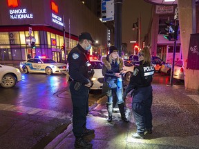 Police stop and question a woman in Montreal at the start of Quebec's curfew intended to help stem the rise of COVID-19 infections on Dec. 31, 2021.