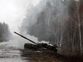 Smoke rises from a Russian tank destroyed by the Ukrainian forces on the side of a road in Lugansk region on February 26, 2022.