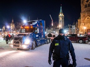 A police officer stands by as a truck leaves Parliament Hill  during a trucker-led protest over pandemic health rules and the Trudeau government in Ottawa on Feb. 18, 2022.