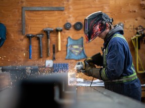 A workers grinds a steel assembly at Macon Industries in Parksville, British Columbia.