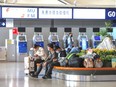 Passengers sit in front of the self-service machines of China Eastern Airlines in Kunming Changshui International Airport in China's southwestern Yunnan province on March 21, 2022, after a China Eastern aircraft flying from Kunming to the southern hub of Guangzhou crashed in southwestern China. (Photo by AFP) / China OUT