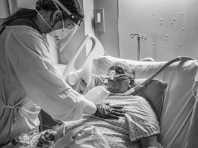 Registered nurse Anne Garcia comforts patient Chuck Dover n the COVID-19 unit of the Peter Lougheed Centre in Calgary. From Leah Hennel's book, Alone Together. Photo by Leah Hennel.