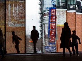 Silhouettes of people are seen against the windows of the Central Library in Calgary on Monday, March 28, 2022.