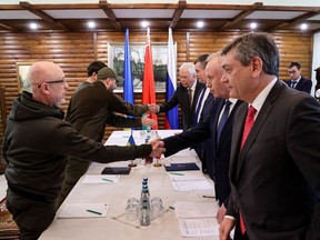 Ukrainian Defence minister Oleksii Reznikov (L) shakes hands with Russian negotiators prior the talks between delegations from Ukraine and Russia in Belarus' Brest region on March 3, 2022, following the Russian invasion of Ukraine. - Russia and Ukraine will discuss a ceasefire at upcoming talks on the border between Poland and Belarus, Moscow's chief negotiator said on March 2, nearly one week into Russia's invasion of its pro-Western neighbour.