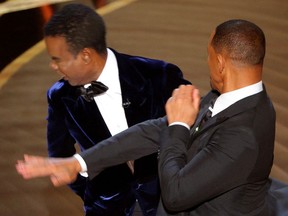 Will Smith (R) hits Chris Rock as Rock spoke on stage during the 94th Academy Awards in Hollywood, Los Angeles, California, U.S., March 27, 2022.