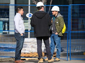 Workers talk at the Brookfield Place building in Calgary on Friday, March 11, 2022. The office tower will be undergoing an engineering review after multiple instances of glass breaking and falling on the street below.