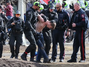 Calgary police make an arrest during an anti-warrant and counter-protester rally in Central Memorial Park on Saturday, March 19, 2022.