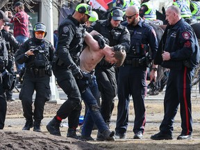 Die Polizei von Calgary nimmt am Samstag, den 19. März 2022, während einer Anti-Mandats- und Gegenprotestkundgebung im Central Memorial Park eine Festnahme vor.