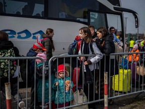 Ukrainian refugees wait to board a bus after crossing the border at Medyka, southeastern Poland, on March 30, 2022. More than four million Ukrainians have fled the country within five weeks to escape Russia's "senseless war," the United Nations said on March 30, 2022.