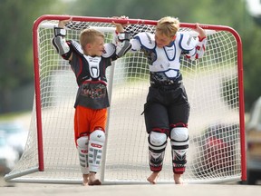 Jake Markowsky, left, and buddy Liam Baxter move a street hockey net in the community of Highwood in 2014.