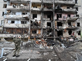 A man takes a picture of a damaged residential building at Koshytsa Street, a suburb of the Ukrainian capital Kyiv, where a military shell allegedly hit, on Feb. 25, 2022.