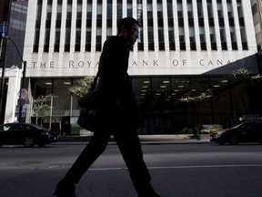 A pedestrian passes in front of a Royal Bank of Canada building in Toronto.