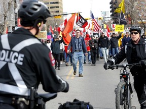 A crowd of protesters walk down a street in Beltline towards police officers on Saturday, March 12, 2022.