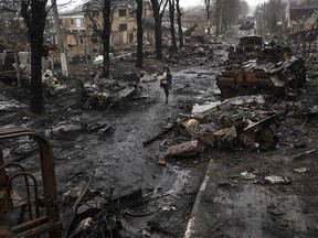 A woman walks amid destroyed Russian tanks in Bucha, in the outskirts of Kyiv, Ukraine, Sunday, April 3, 2022.