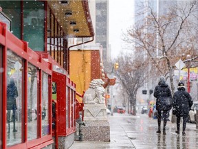 Pedestrians walk in Calgary's Chinatown as showers fall Tuesday, April 19, 2022.