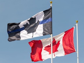 A thin blue line flag is seen flying next to a Canadian flag over the Edmonton Police Association building. In Calgary, the police commission has ordered removal of the thin blue line patch on police uniforms. The association has refused.