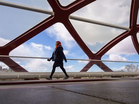 A woman walks across the Peace Bridge during a sunny day in Calgary on Wednesday, April 6, 2022.