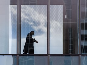 An office worker checks his watch while crossing a Plus-15 in downtown Calgary on Wednesday, April 6, 2022.