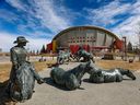 The By the Banks of the Bow statue in Stampede Park frames the Scotiabank Saddledome on Monday, April 4, 2022.