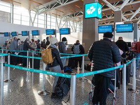 Travellers wait to check in for their flight at Calgary International Airport on Dec. 27, 2021.