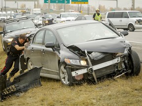 Police help push a damaged car back onto Deerfoot Trail so it can be towed away after a crash near Southland Drive.