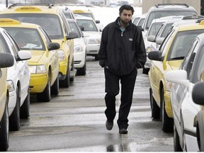 Taxi driver Fukhjinder Nagra walks through a parking lot full of waiting cabs at the Calgary International Airport on March 24.