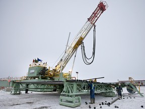 Workers remove caps from drill pipes on a Precision Drilling rig near Alix, Alta., Canada, on Dec. 19, 2009.