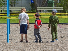 Kids check out caution tape at a playground in Bridgeland, closed by the City of Calgary in response to the COVID-19 pandemic on May 28, 2020.