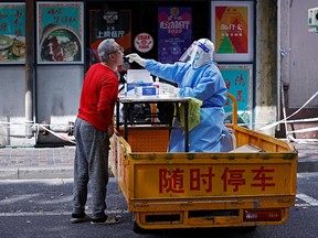 A medical worker collects a swab from a resident for testing amid a COVID-19 outbreak in Shanghai, China, on April 22, 2022.