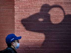 A pedestrian walks past a shadow of a ram’s head sculpture in Toronto’s Chinatown on March 10, 2022.