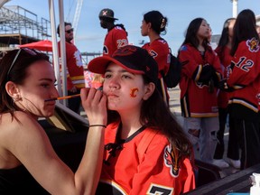 Fifteen-year-old Kiarrah has her face painted by Avery Towle before the game 7 of the first round of play-off action between Calgary Flames and Dallas Stars at the Red Lot outside Scotiabank Saddledome on Sunday, May 15, 2022.