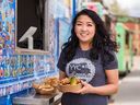 The Dumpling Hero food truck co-owner Tracy Cheng poses for a photo holding a Pig-cle Sandwich at the Calgary Stampede midway food launch event on Tuesday, May 17, 2022. 