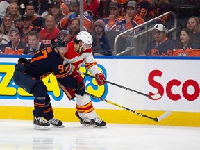 Connor McDavid #97 of the Edmonton Oilers defends against Johnny Gaudreau #13 of the Calgary Flames during the first period in Game 4 of the second round of the 2022 Stanley Cup Playoffs at Rogers Place on May 24, 2022 in Edmonton, Canada.