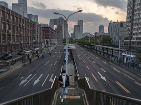 A commuter walks away from a bus stop as traffic is light on the road during the evening rush hour near the central business district after the local government issued a work-from-home order May 9, 2022 in Beijing, China.