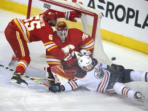 Edmonton Oilers defenceman Brett Kulak crashes into the net in front of Calgary Flames goaltender Jacob Markstrom and defenceman Noah Hanifin at Scotiabank Saddledome on March 26, 2022.