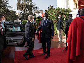 Senegal's President Macky Sall (C) greets United Nations (UN) Secretary-General Antonio Guterres (L)  as he arrive at the Presidential palace during his West Africa tour, in Dakar, on May 1, 2022.