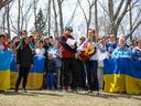 Guests at a BBQ picnic for Ukrainians fleeing war take part in a flash mob singing of the Ukrainian military anthem at Bowness Park in Calgary on Sunday, May 1, 2022. 