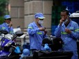 Workers take rapid antigen tests for COVID-19 on a street during lockdown, amid the COVID-19 pandemic, in Shanghai, China, Friday, May 20, 2022.