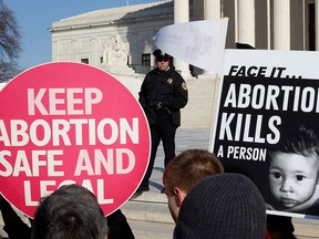 A police officer watches pro-life and pro-choice supporters demonstrating to mark the anniversary of the Supreme Court's 1973 Roe v. Wade abortion decision in Washington, Jan. 24, 2011.