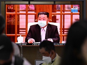 People sit near a screen showing a news broadcast at a train station in Seoul on May 12, 2022, of North Koreas leader Kim Jong Un appearing in a face mask on television for the first time to order nationwide lockdowns after the North confirmed its first-ever Covid-19 cases. (Photo by Anthony WALLACE / AFP)