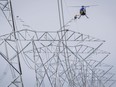 A lineman reaches for a lift from a helicopter on powerlines near Carstairs, Alta., on July 23, 2014. Alberta's utilities watchdog has shut down a plan from AltaLink to give ratepayers a refund.