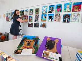 Foundations for the Future Charter Academy teacher Rebecca Carruthers-Green hangs some of her Grade 4 students' art from the Empathy Pawject at the Central Library on Thursday, May 26, 2022. The project had students paint portraits of dogs that were up for adoption at local animal rescue societies to help find homes for the dogs.
